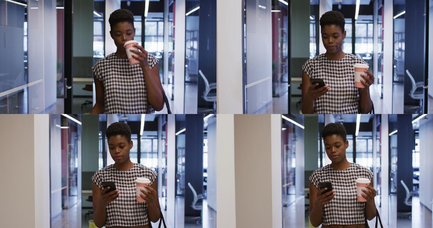 非裔美国女商人拿着智能手机在办公室走廊里走着