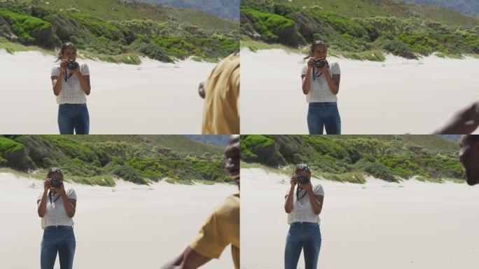 一位非洲裔美国妇女在海滩上用数码相机拍下她丈夫的照片