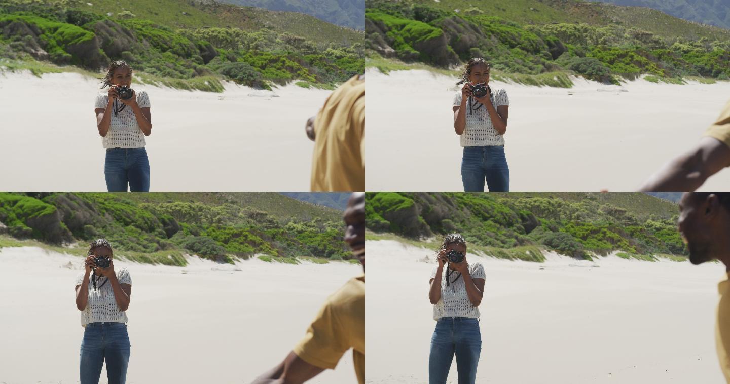一位非洲裔美国妇女在海滩上用数码相机拍下她丈夫的照片
