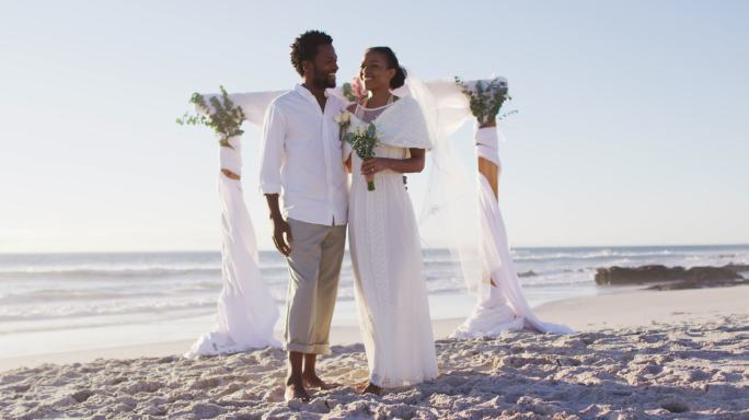 非洲裔美国人在海滩上对着镜头微笑，相爱的夫妇