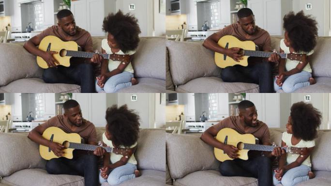 一位非裔美国父亲和他的女儿坐在沙发上弹吉他