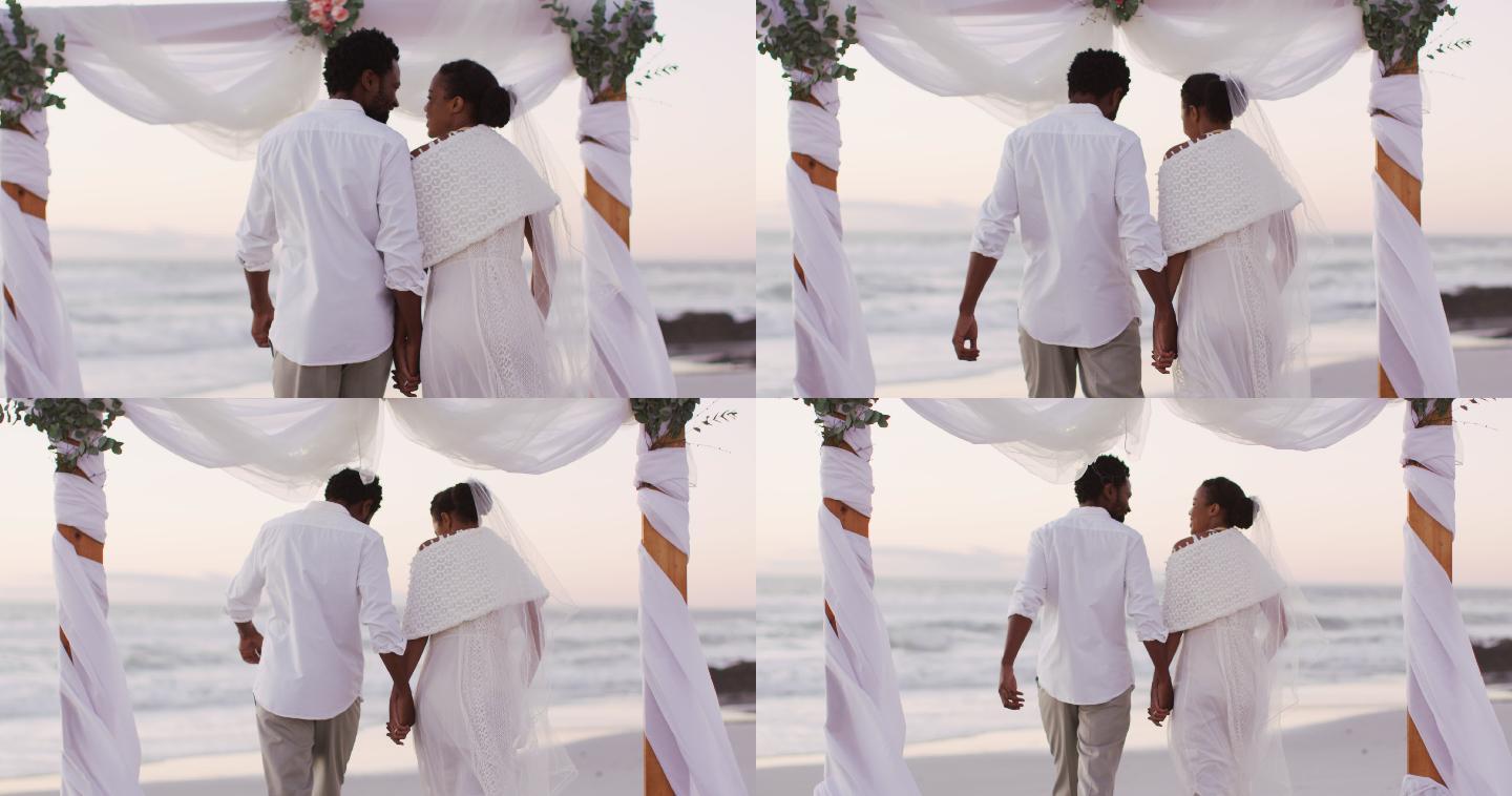非裔美国情侣结婚，手牵着手在海滩上散步
