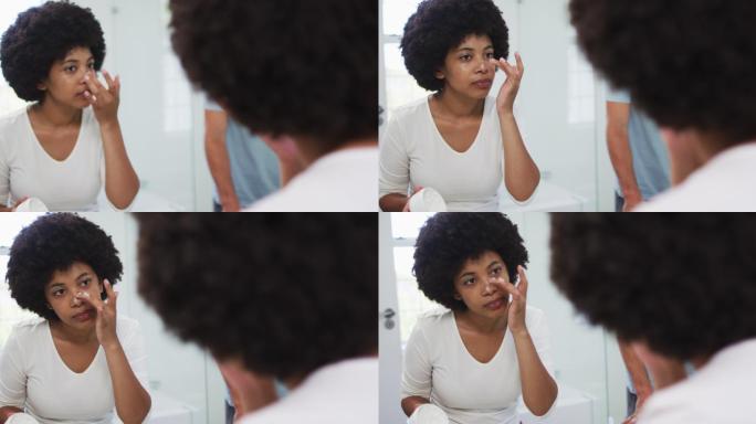 一位非裔美国妇女在家照镜子时涂面霜