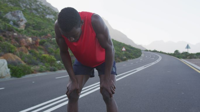 一个非裔美国人在山路上锻炼，在跑步过程中停下来休息