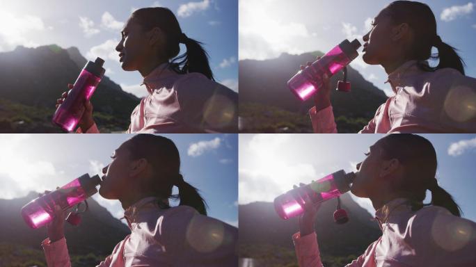 一位非洲裔美国妇女在山里徒步时喝瓶子里的水