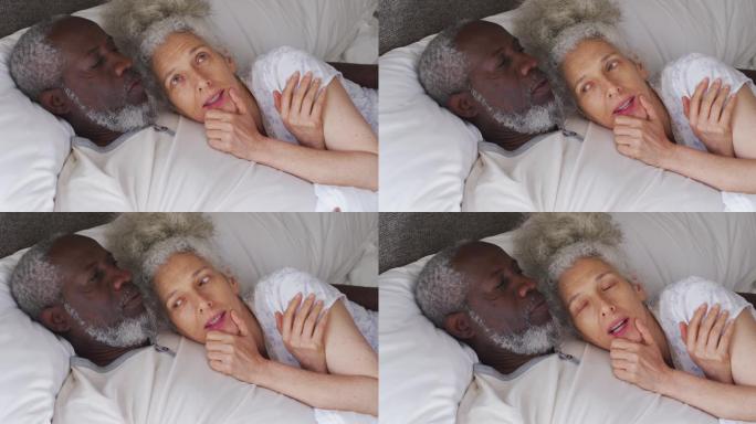 一对跨种族的老年夫妇一起睡在家里的床上