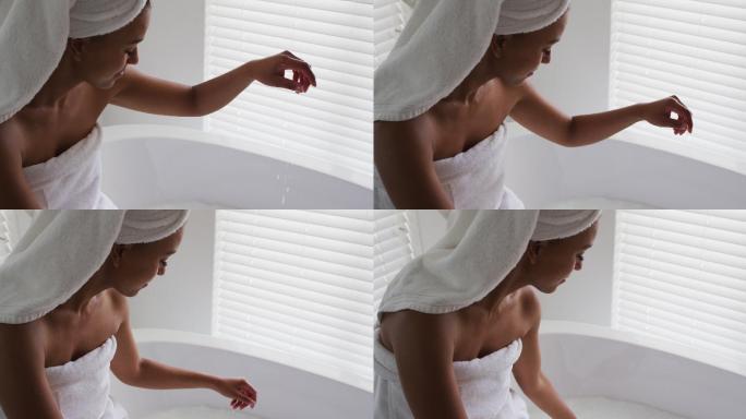 一位非裔美国妇女在自家浴室的浴缸里摸水