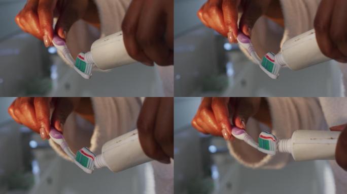近距离观察非洲裔美国妇女把牙膏放在她的牙刷在浴室