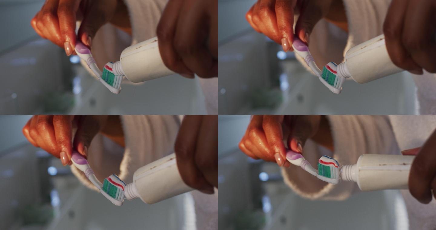 近距离观察非洲裔美国妇女把牙膏放在她的牙刷在浴室