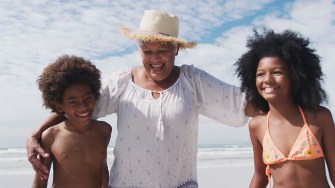 混合种族老年妇女的肖像与孙子在海滩微笑