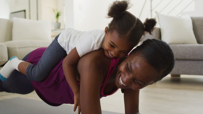 快乐的非裔美国母亲和女儿在家里做运动