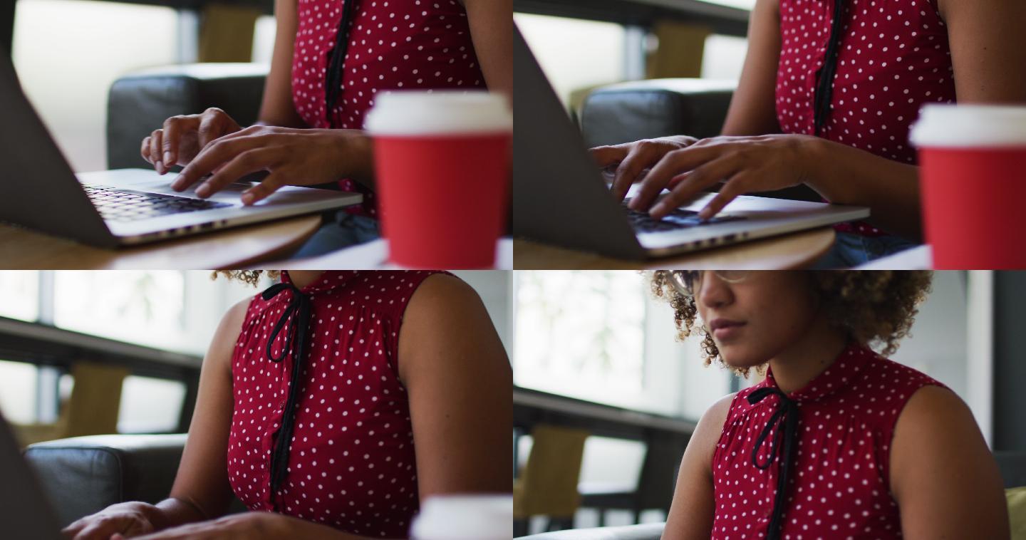 混血儿女性在办公室用笔记本电脑写文件，喝咖啡