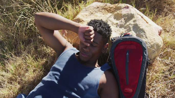 一个非裔美国人在户外运动，在乡间的山上休息和躺着