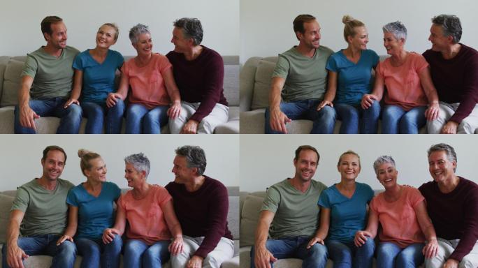 幸福的白种夫妇和年长的父母或家人坐在沙发上对着镜头微笑交谈