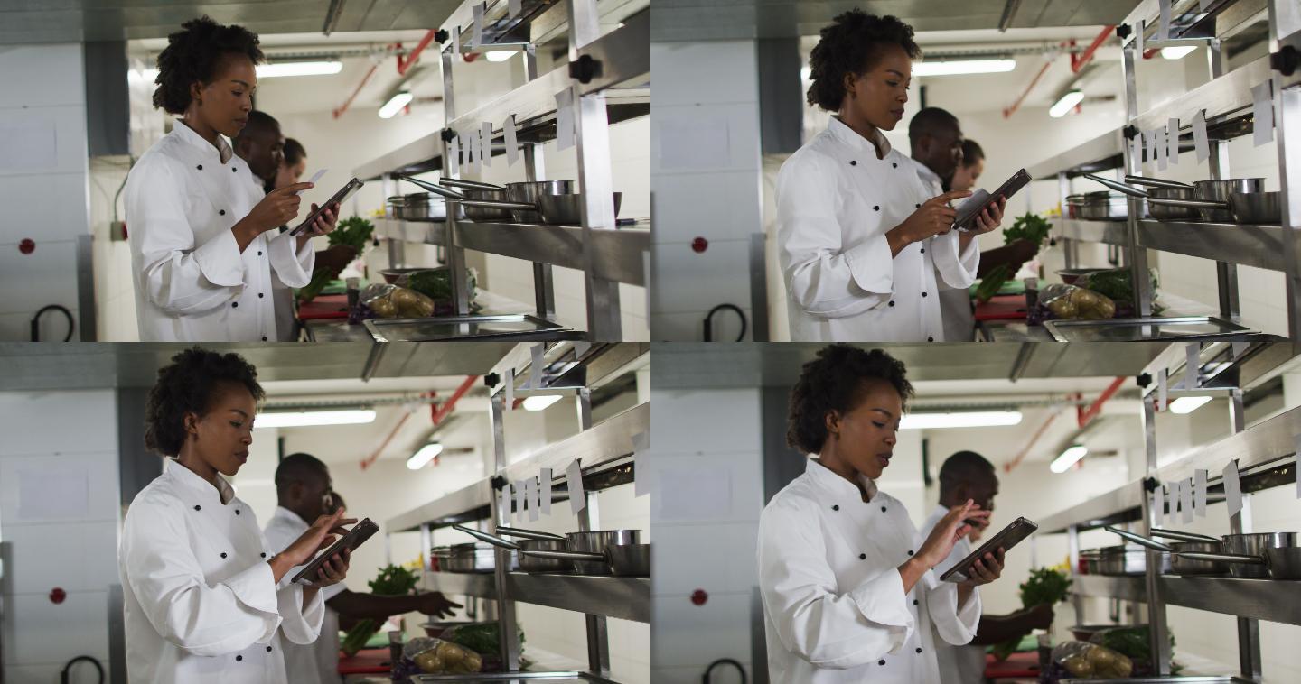 非裔美国女厨师在餐厅厨房里接单和使用平板电脑
