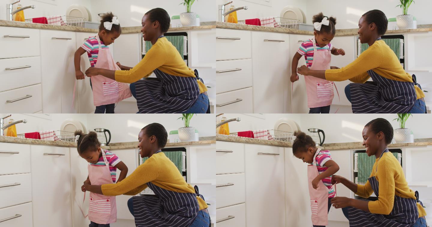 快乐的非裔美国母女穿着围裙在厨房里