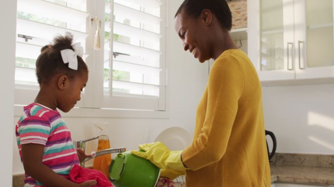 快乐的非裔美国母亲和女儿在厨房洗盘子