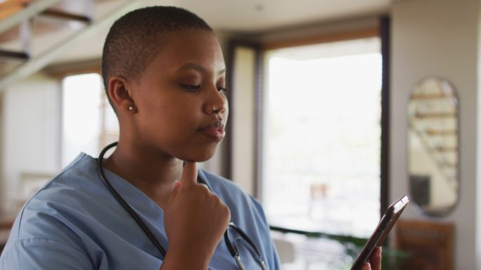 非裔美国女医生正在用平板电脑看摄像机进行视频通话咨询