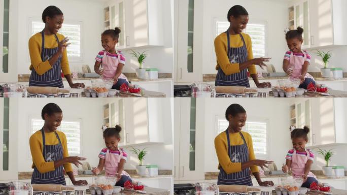 快乐的非裔美国母亲和女儿穿着围裙在厨房里做饭