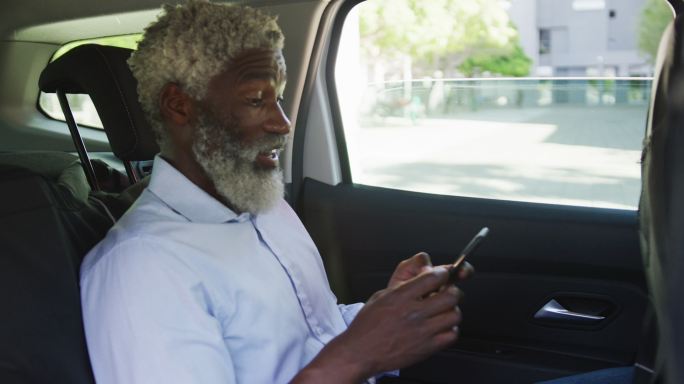 非裔美国老人坐在车里用智能手机