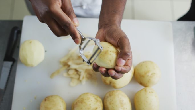 非洲裔美国女厨师在餐厅厨房削土豆的腹部