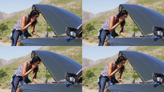 一位非洲裔美国妇女在路上用智能手机说话，站在她抛锚的车旁边