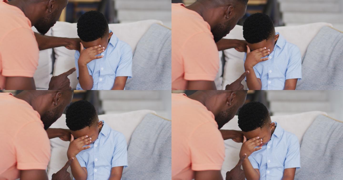 一位非裔美国父亲在沙发上责备他的儿子