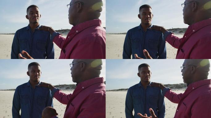 一位非裔美国父亲和十几岁的儿子站在海滩上，手放在他的肩膀上说话