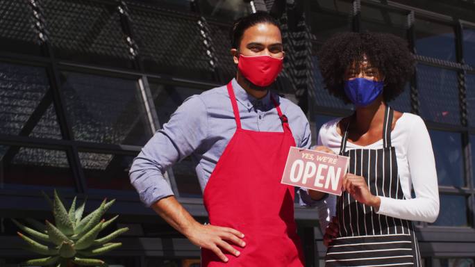 不同的咖啡馆工作人员戴着口罩，展示着开放的标牌