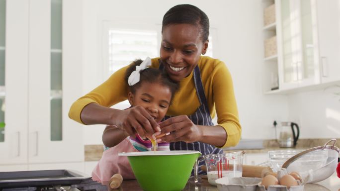快乐的非裔美国母女穿着围裙在厨房做饭