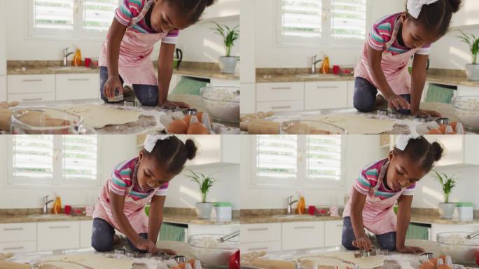 快乐的非洲裔美国女孩在厨房里用切饼干的刀