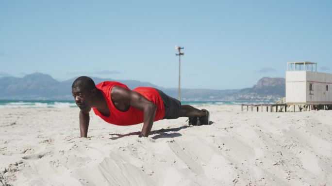 非裔美国人在沙滩上做俯卧撑，在海边做户外运动