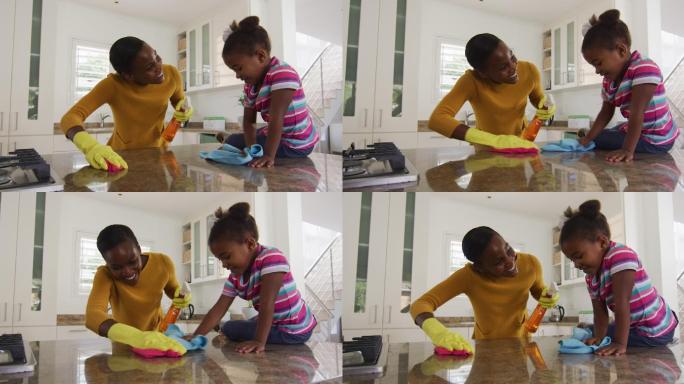 非裔美国母亲和女儿在厨房里打扫台面和欢笑