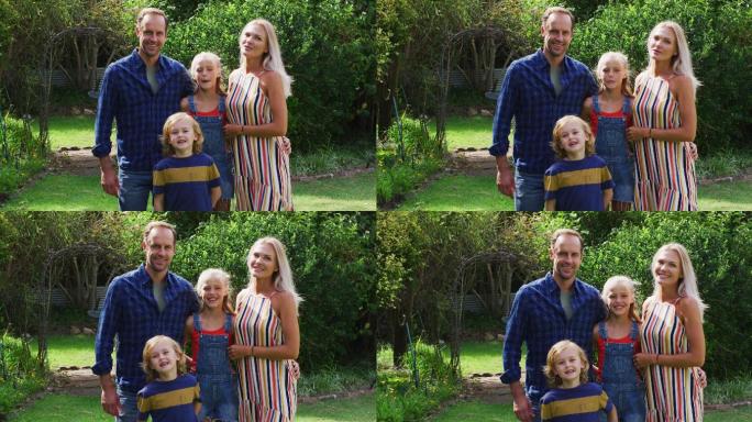 白人父母与儿子和女儿站在花园微笑的肖像