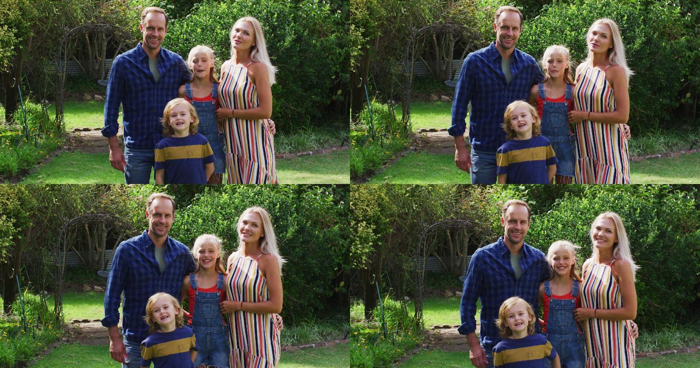 白人父母与儿子和女儿站在花园微笑的肖像