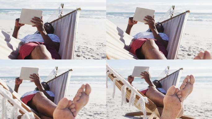非洲裔美国人躺在沙滩上的吊床上使用电子平板电脑