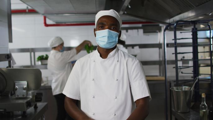 非裔美国男厨师戴着口罩双臂交叉的肖像