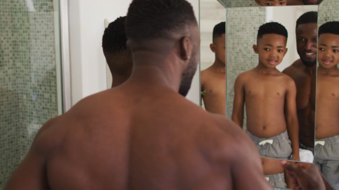 一对非裔美国父子对着镜子一起秀肌肉