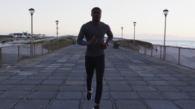 专注的非裔美国人在户外锻炼，在海边跑步
