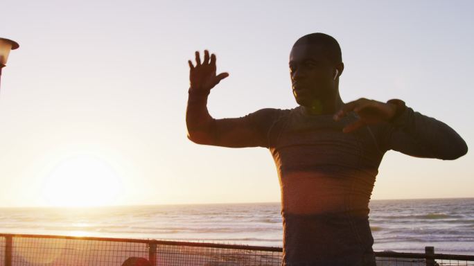 专注的非裔美国人在日落时分在海边伸展运动