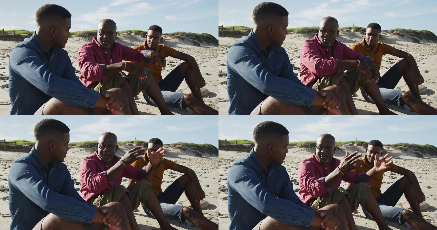 一位非洲裔美国老人和一对十几岁的儿子坐在沙滩上聊天