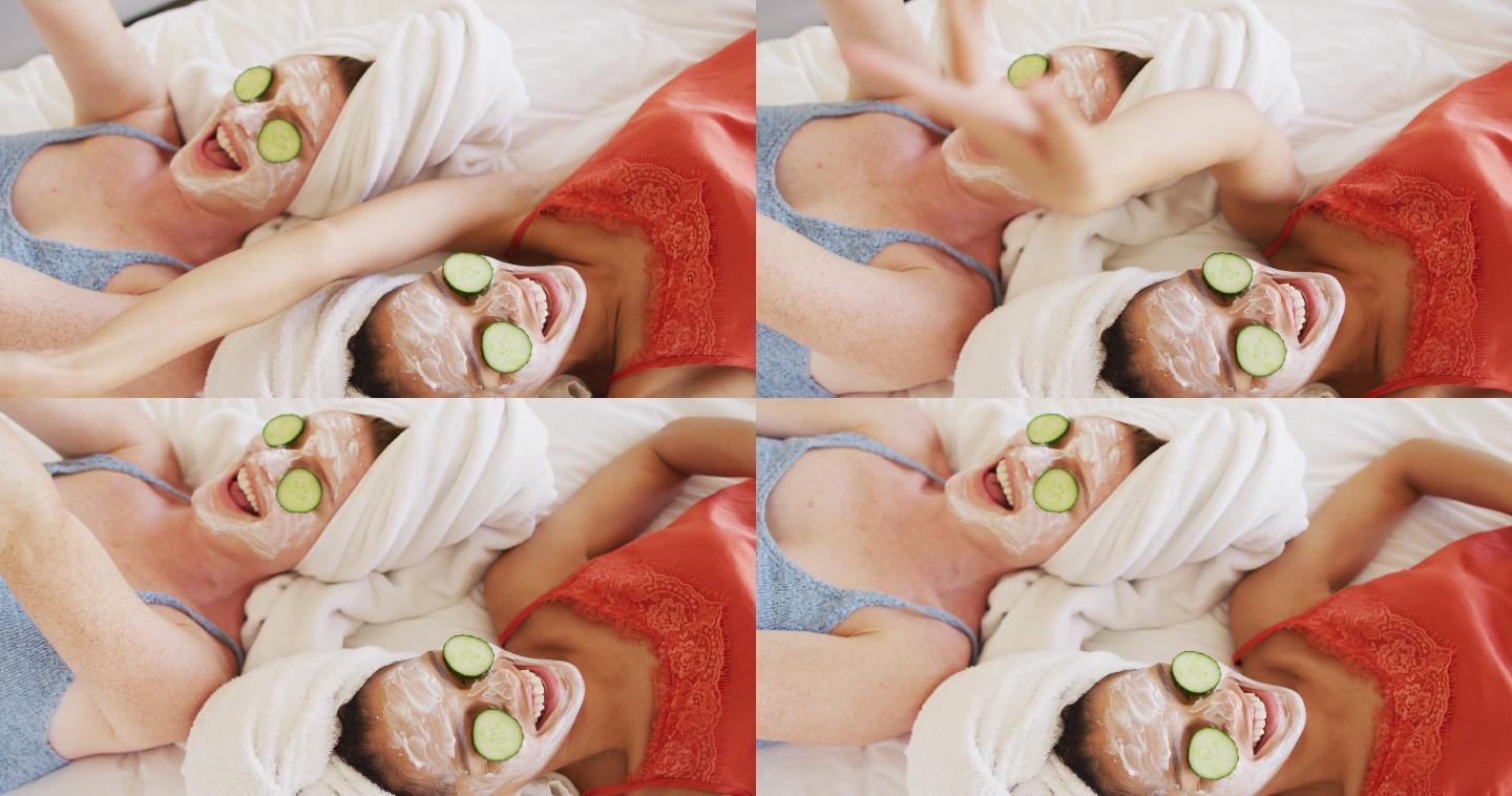 快乐的女性朋友们头上戴着毛巾，眼睛上抹着黄瓜躺在床上