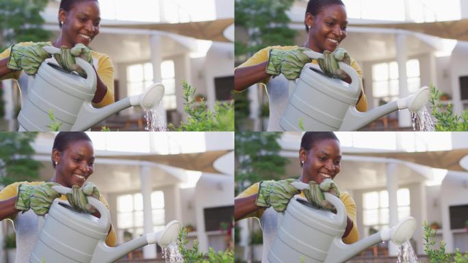 快乐的非裔美国妇女戴着手套在花园里浇花