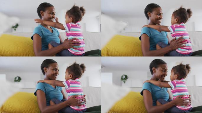 快乐的非裔美国母亲和女儿坐在沙发上，抚摸着额头