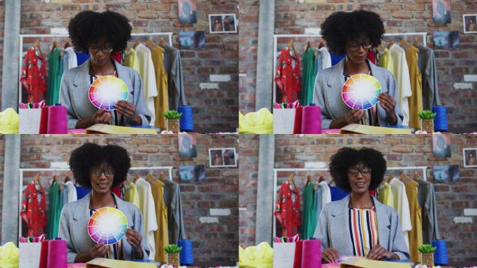 非裔美国女时装设计师展示颜色托盘看着相机和微笑