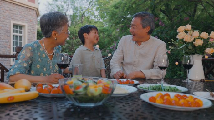 快乐的祖孙三人在庭院里用餐