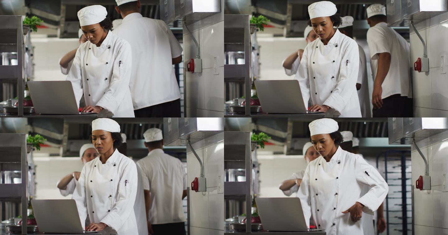 非裔美国女厨师在餐厅厨房使用笔记本电脑
