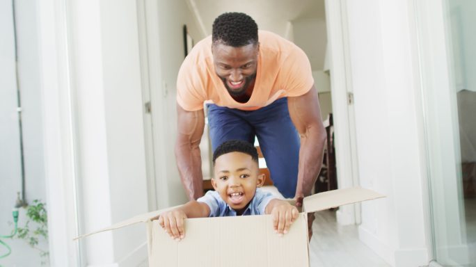 一对非裔美国父子在走廊里玩一个纸板箱