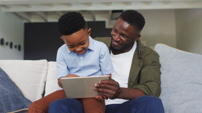 非裔美国人父亲和儿子一起使用数码平板电脑