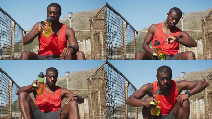 非裔美国人，坐着，喝着水瓶，在户外运动中休息